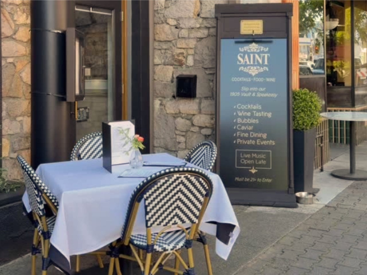 Outdoor restaurant table beside stone wall and sign