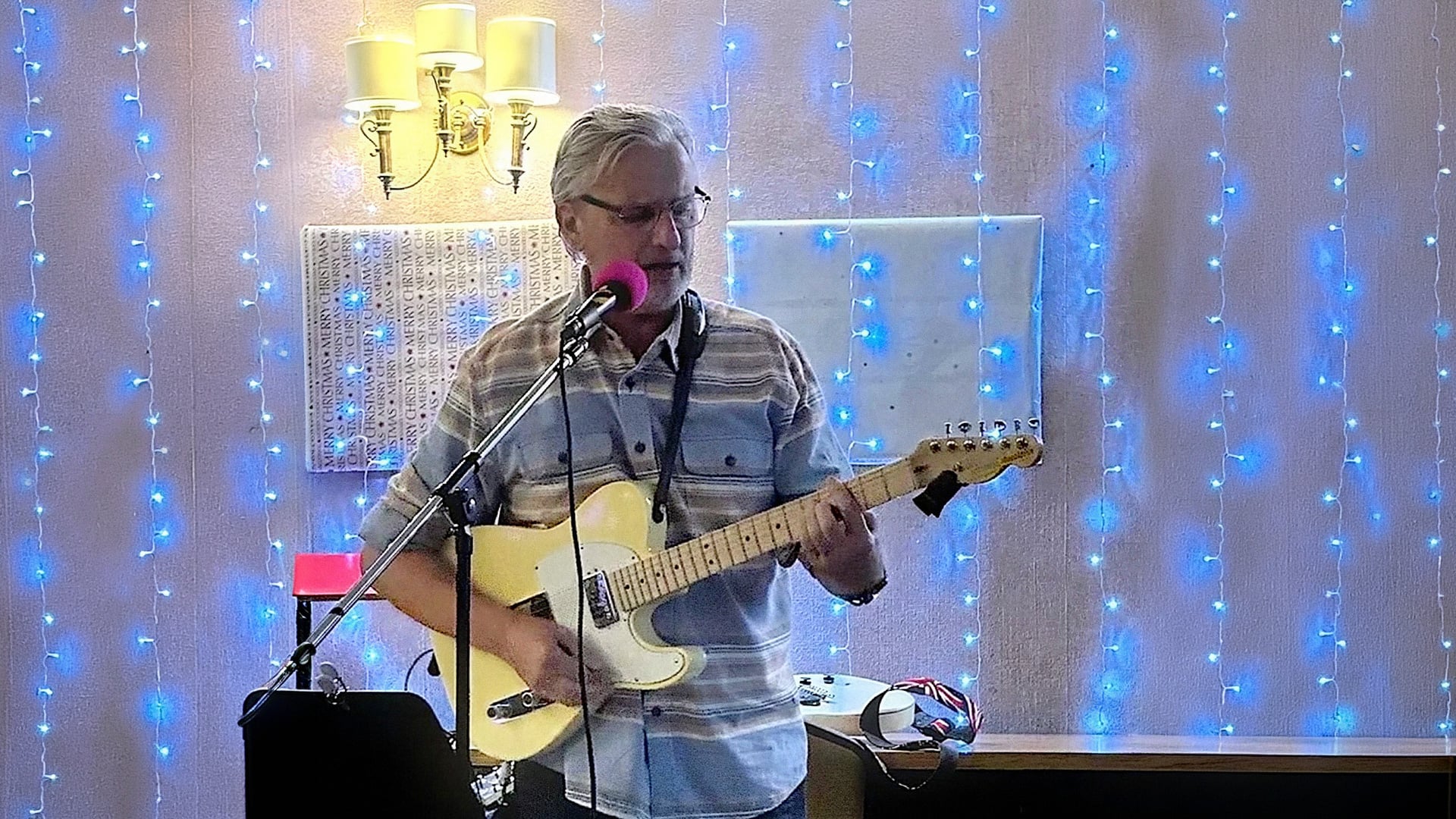 Man sings and plays electric guitar under blue lights