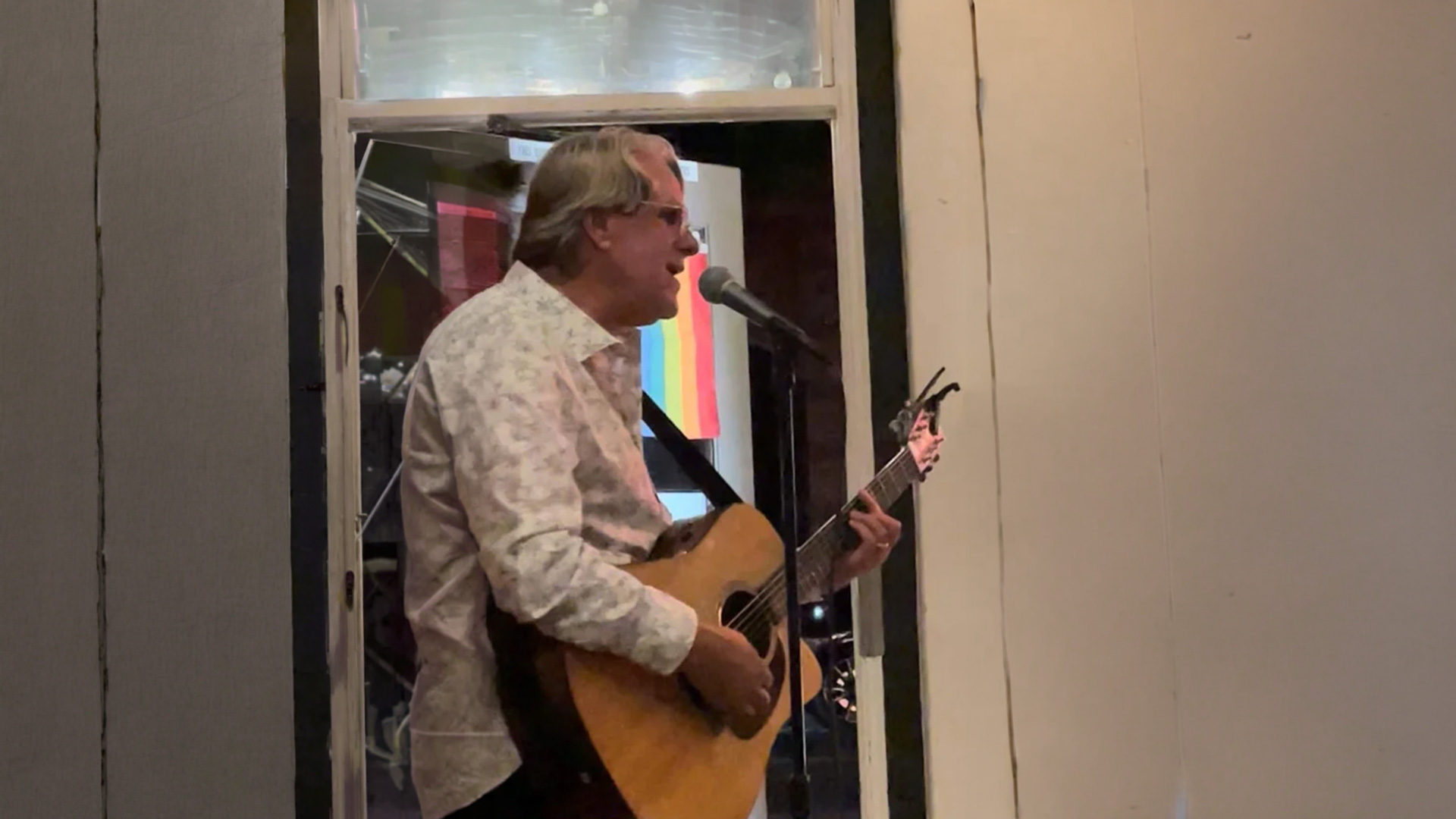 Man singing and playing acoustic guitar at microphone