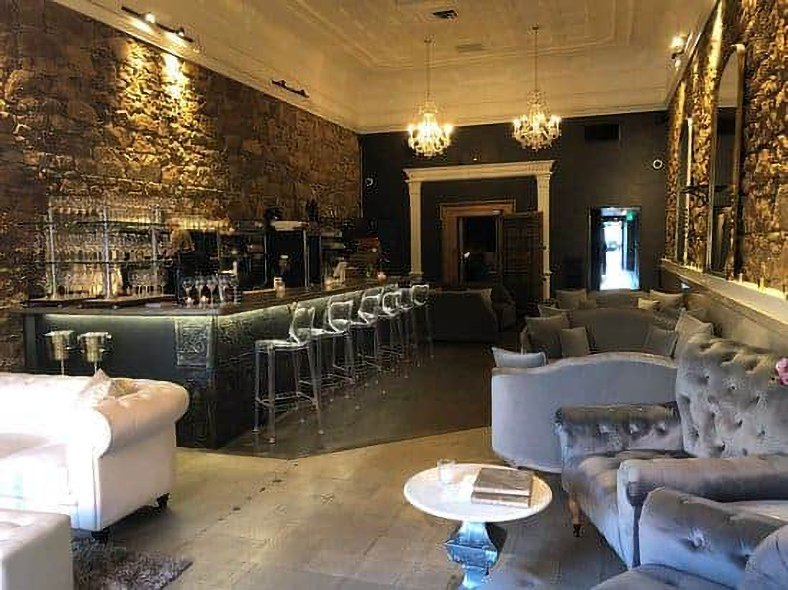 Elegant lounge and bar with stone walls and chandeliers.