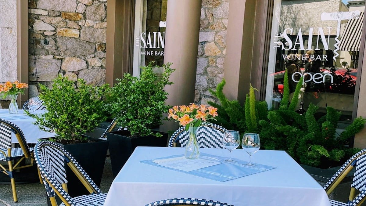 Outdoor seating at a wine bar with plants.