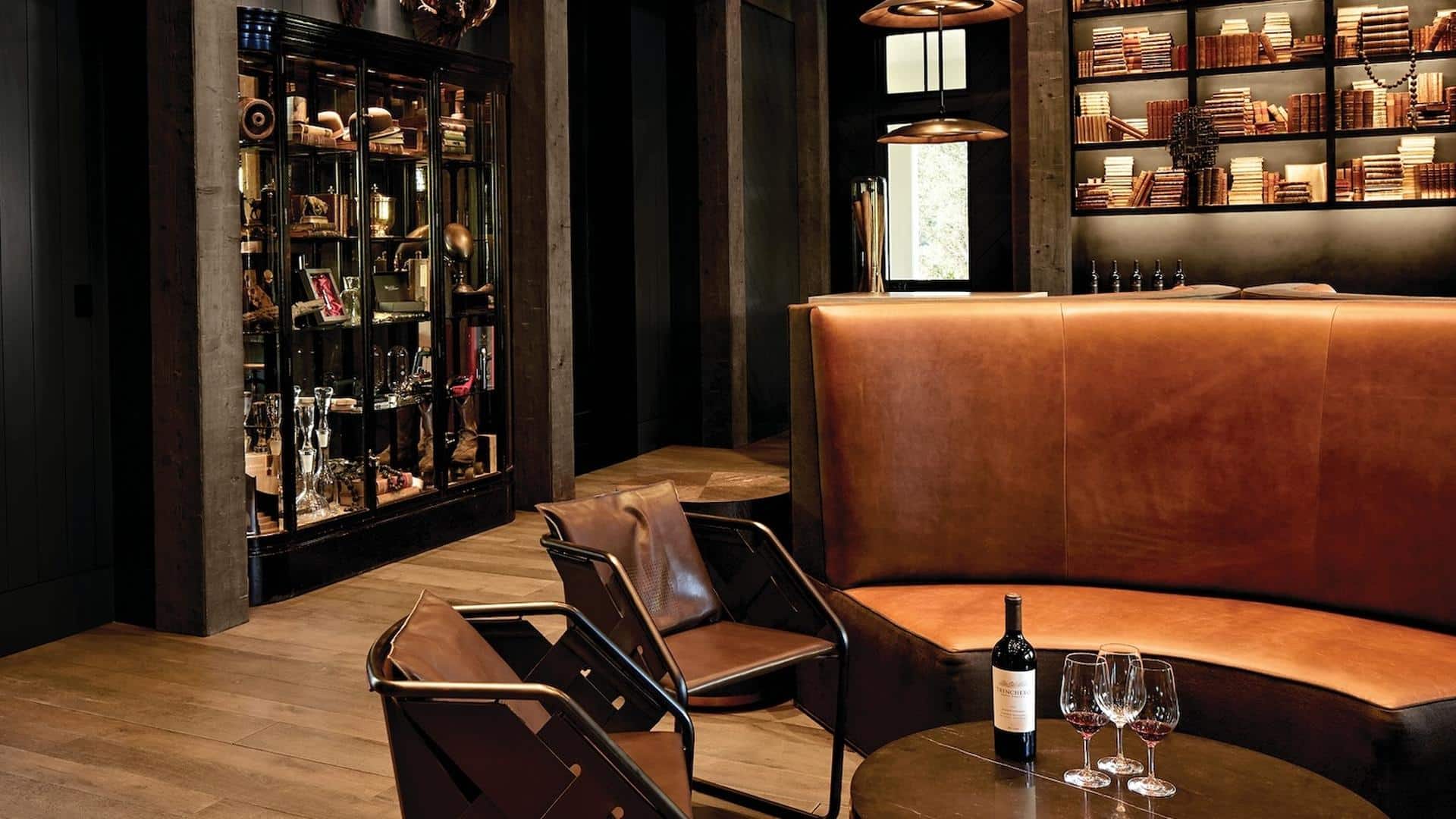 Cozy lounge with leather chairs and wine bottle.