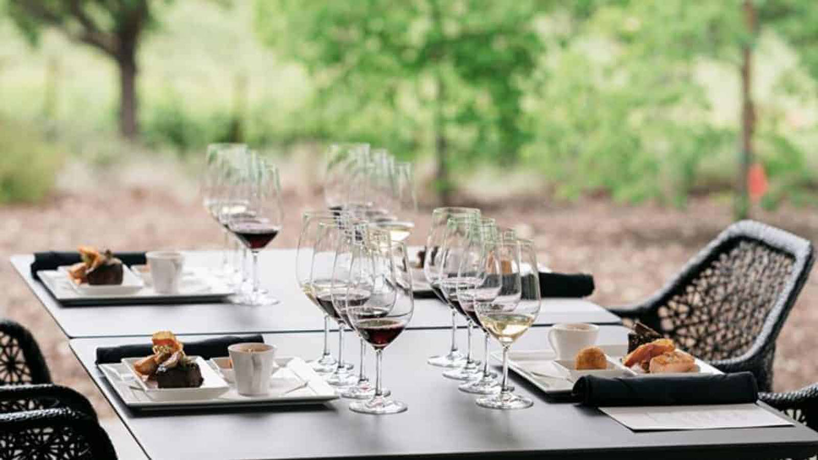 Outdoor table with wine glasses and appetizers.