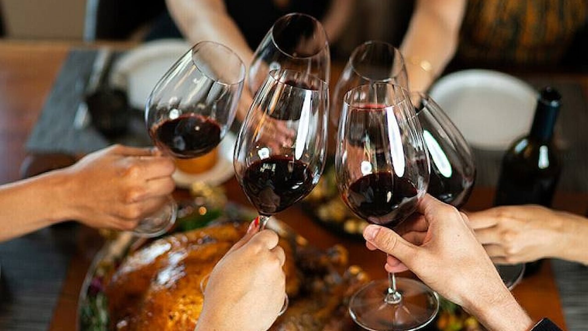 Group toasting with red wine over dinner