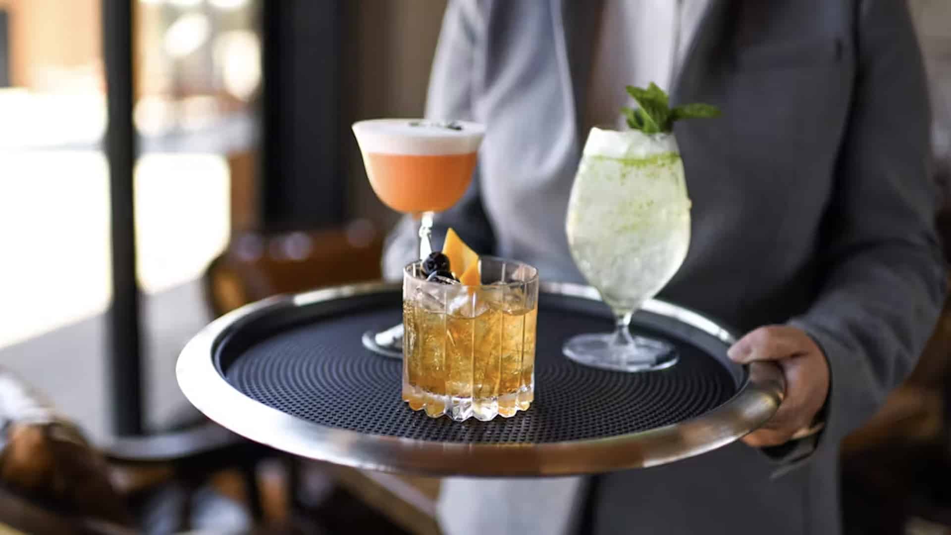 Server holding tray with mixed drinks.