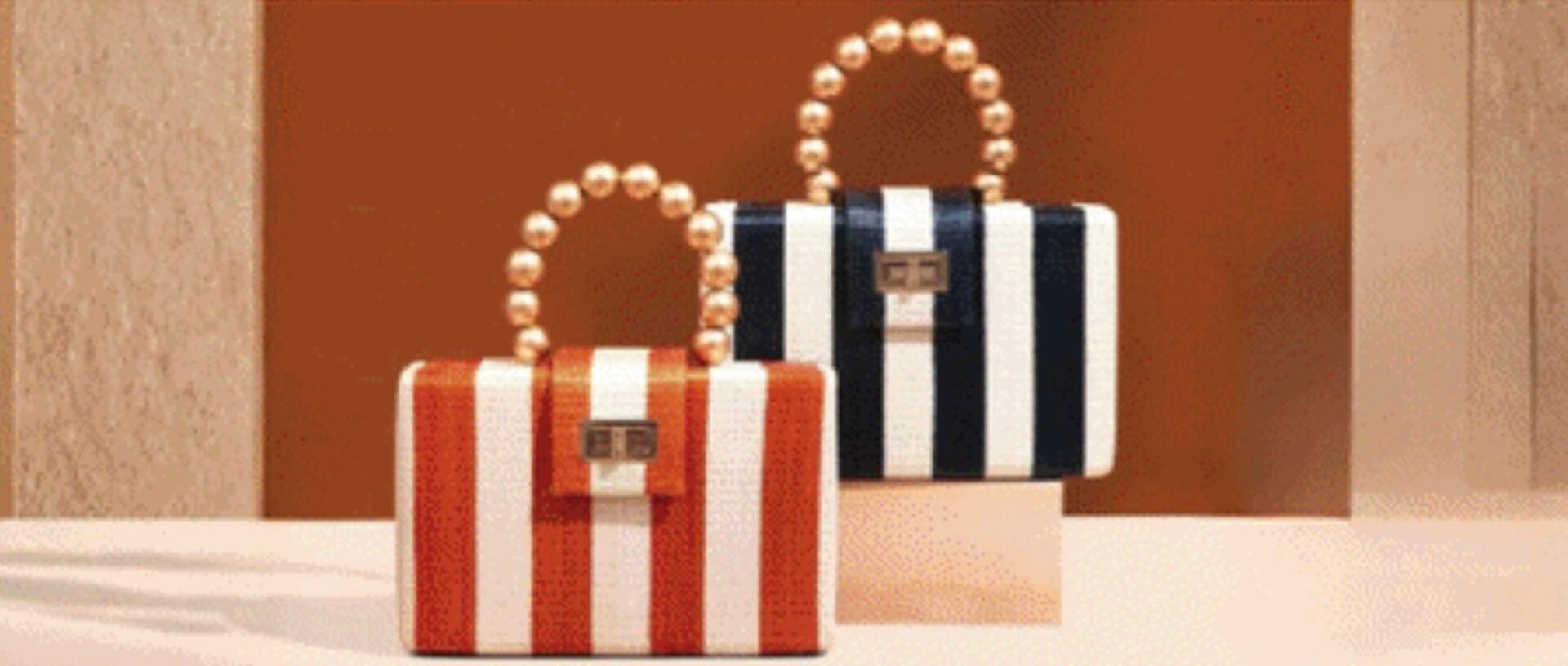 Two striped handbags with pearl handles on display