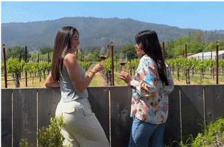 Two women chatting with wine in vineyard