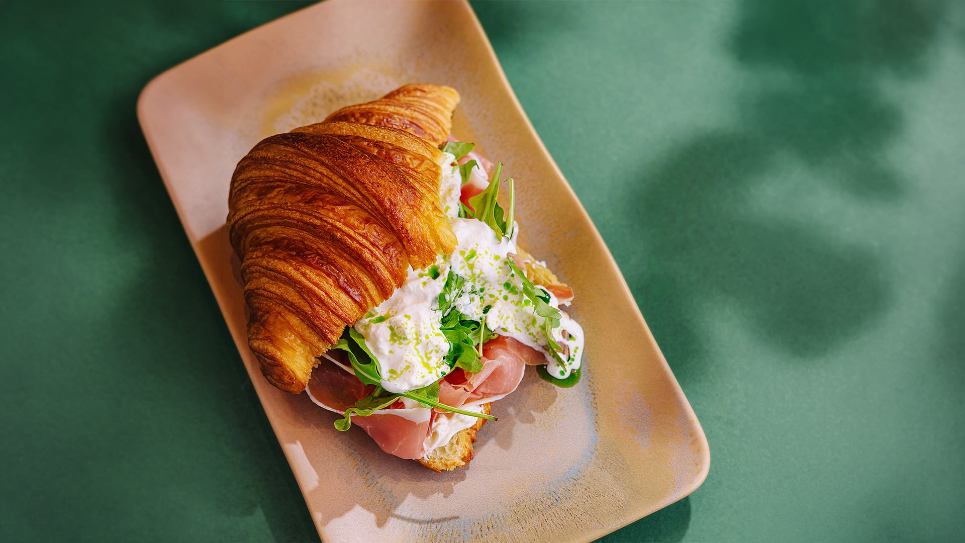 Prosciutto and arugula croissant sandwich on a plate