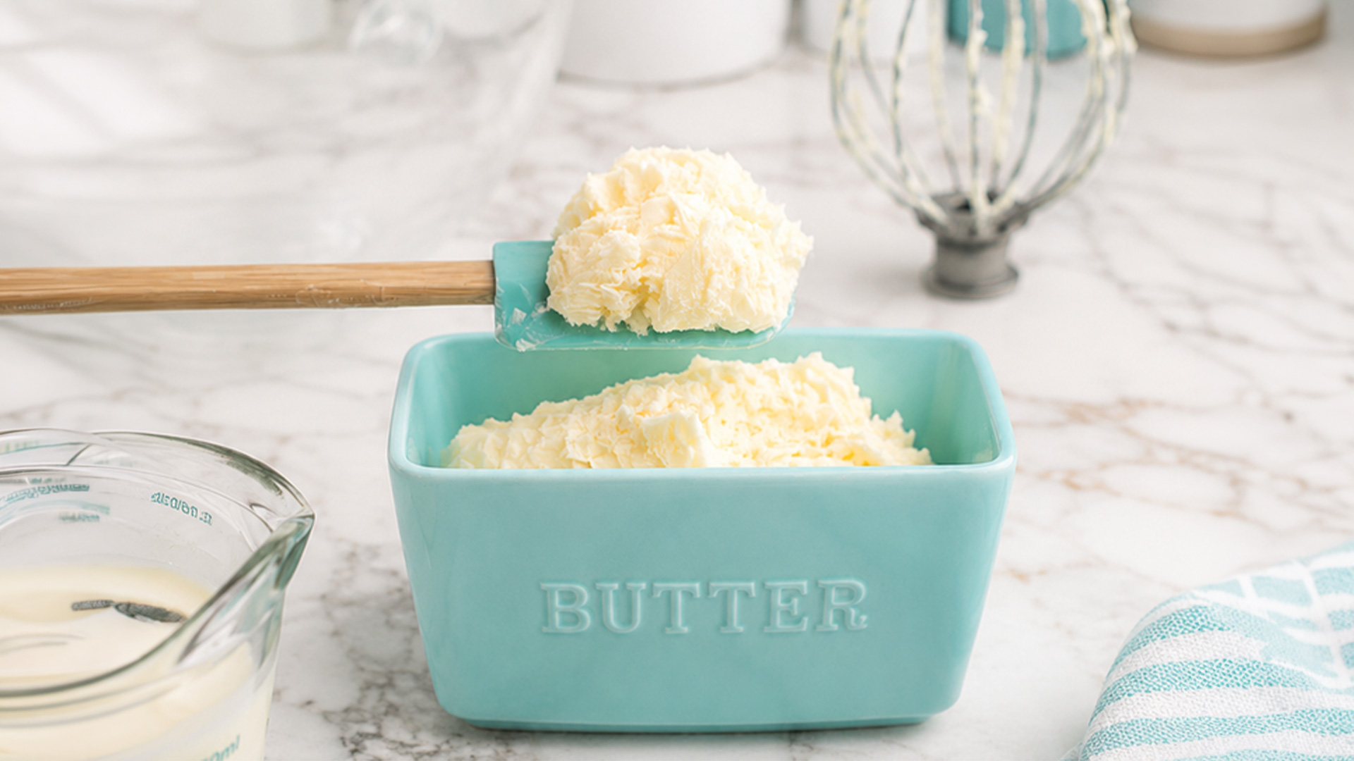 Butter on spatula above turquoise butter dish