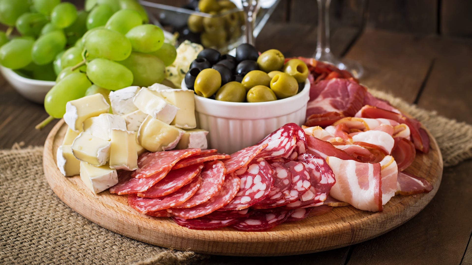 Charcuterie board with cured meats, cheeses, olives, and grapes