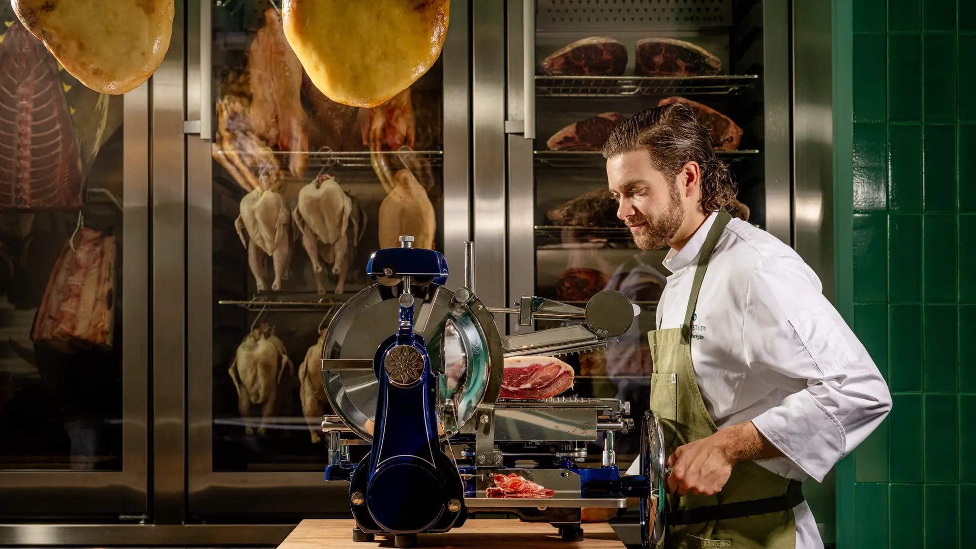 Chef slicing cured ham in dry aging room