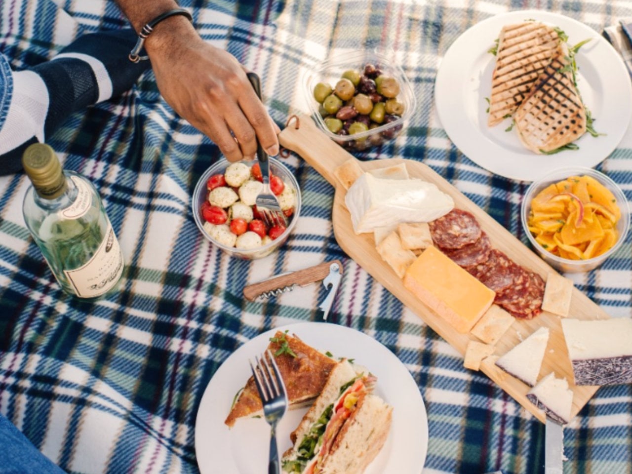 Picnic spread with wine, cheese, and sandwiches