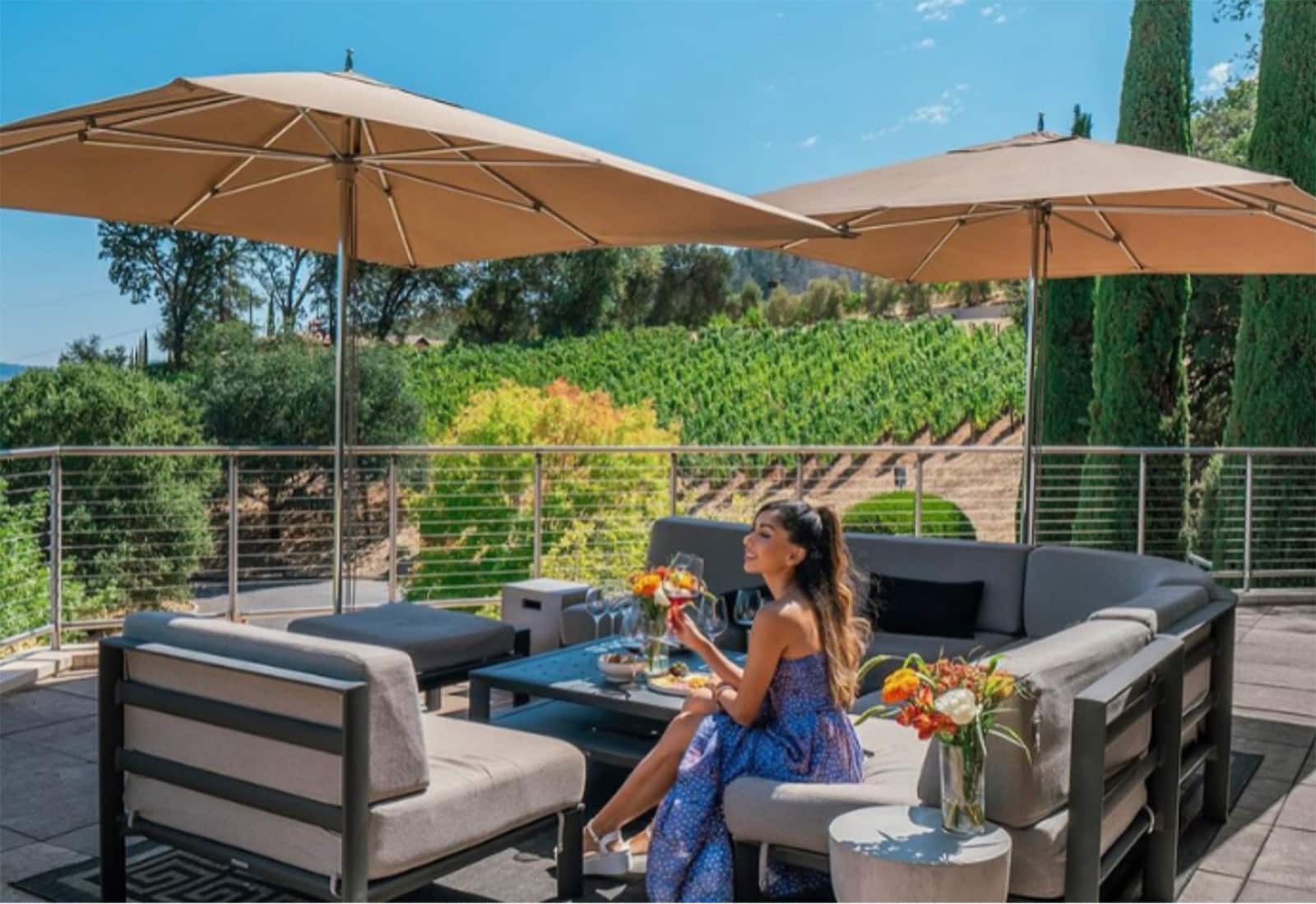 Woman enjoying wine on vineyard patio.