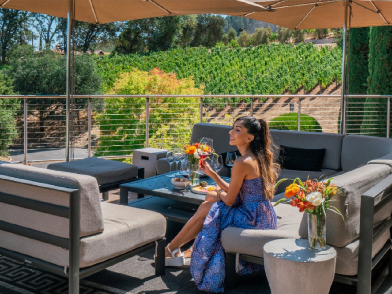 Woman enjoying wine on patio overlooking vineyard
