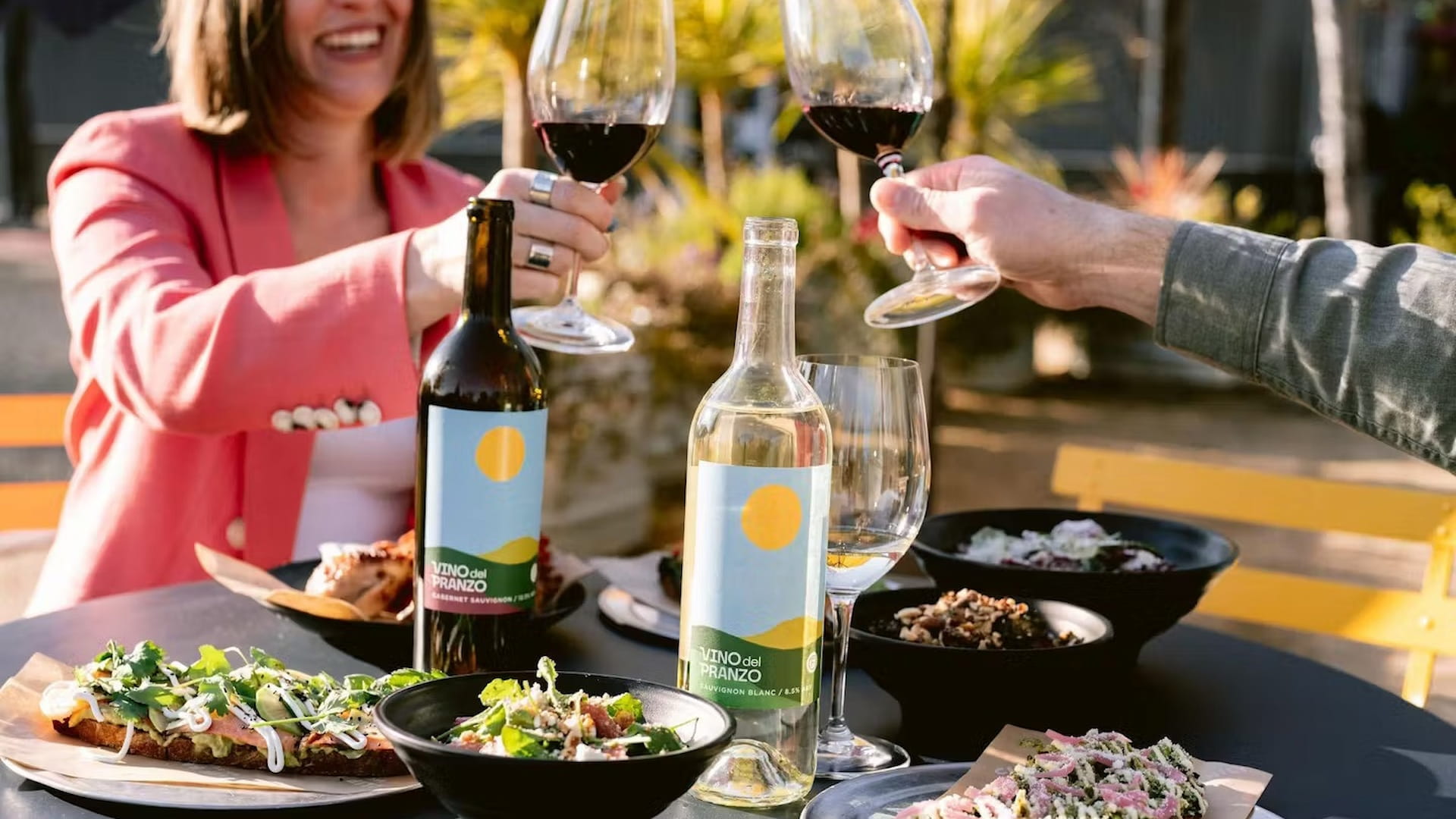 Friends toasting with wine at outdoor meal.