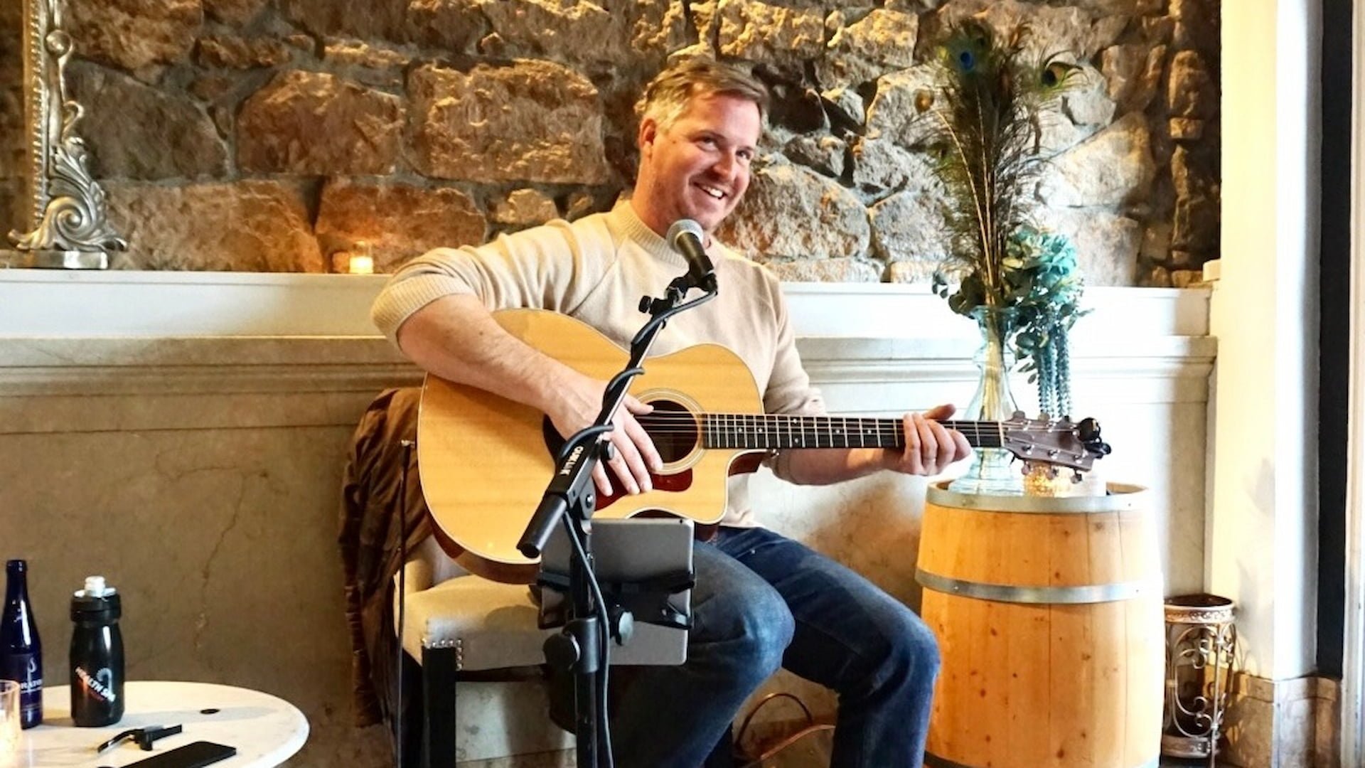 Smiling man playing acoustic guitar indoors.