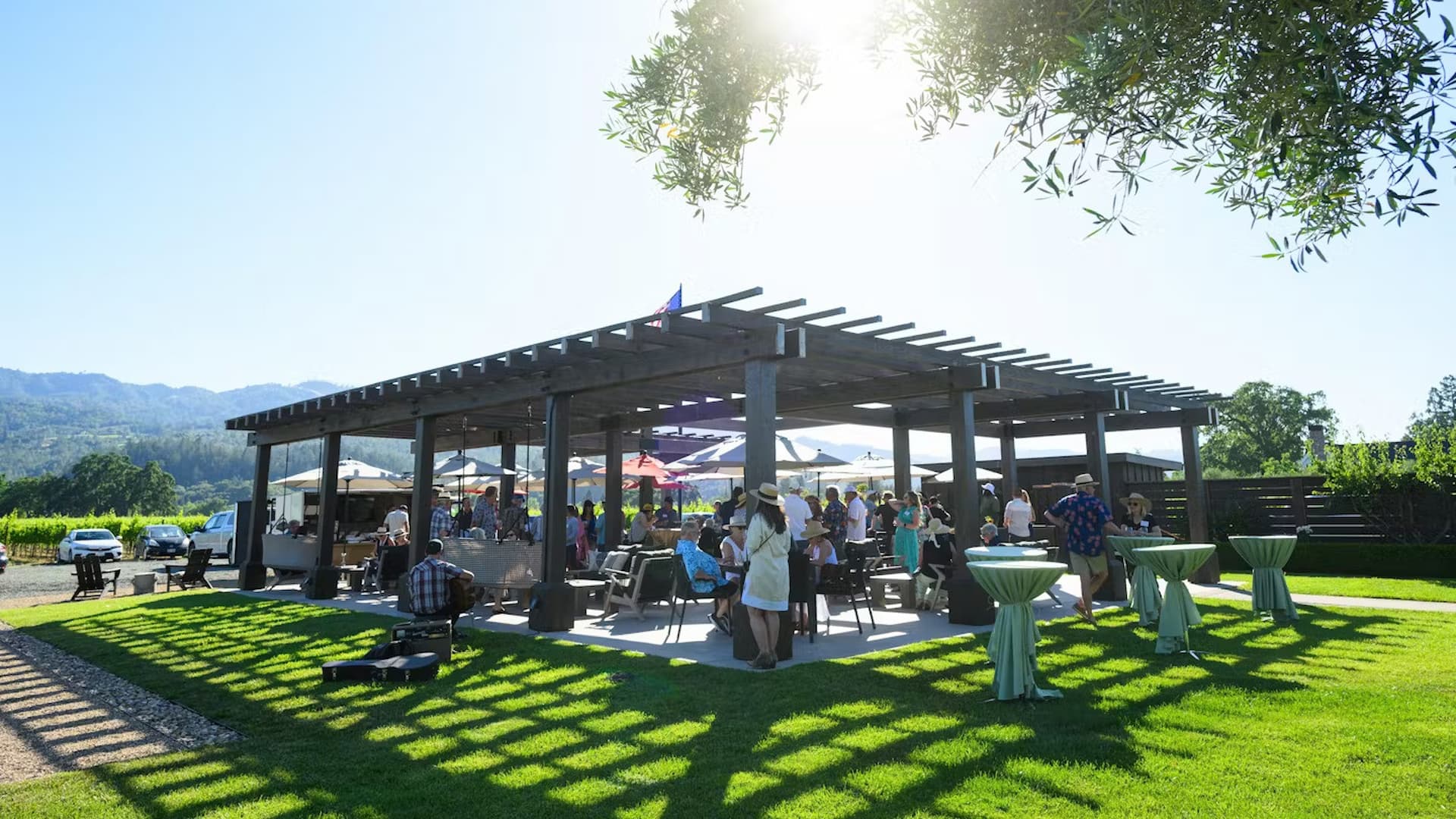 Outdoor gathering under a pergola on a sunny day.