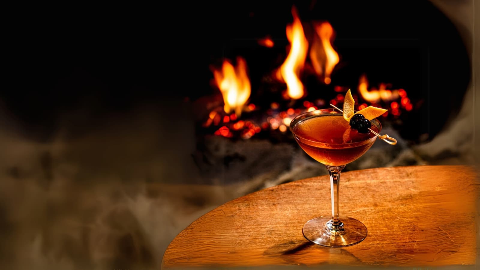 Cocktail by a cozy fireplace on a table.