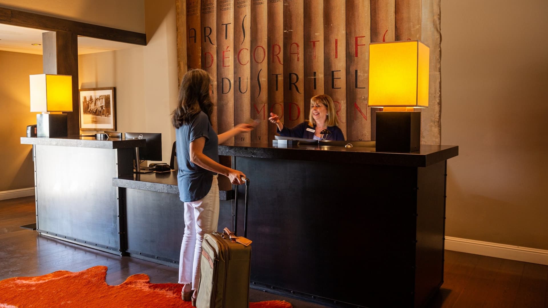 Hotel check-in desk with guests and receptionist.