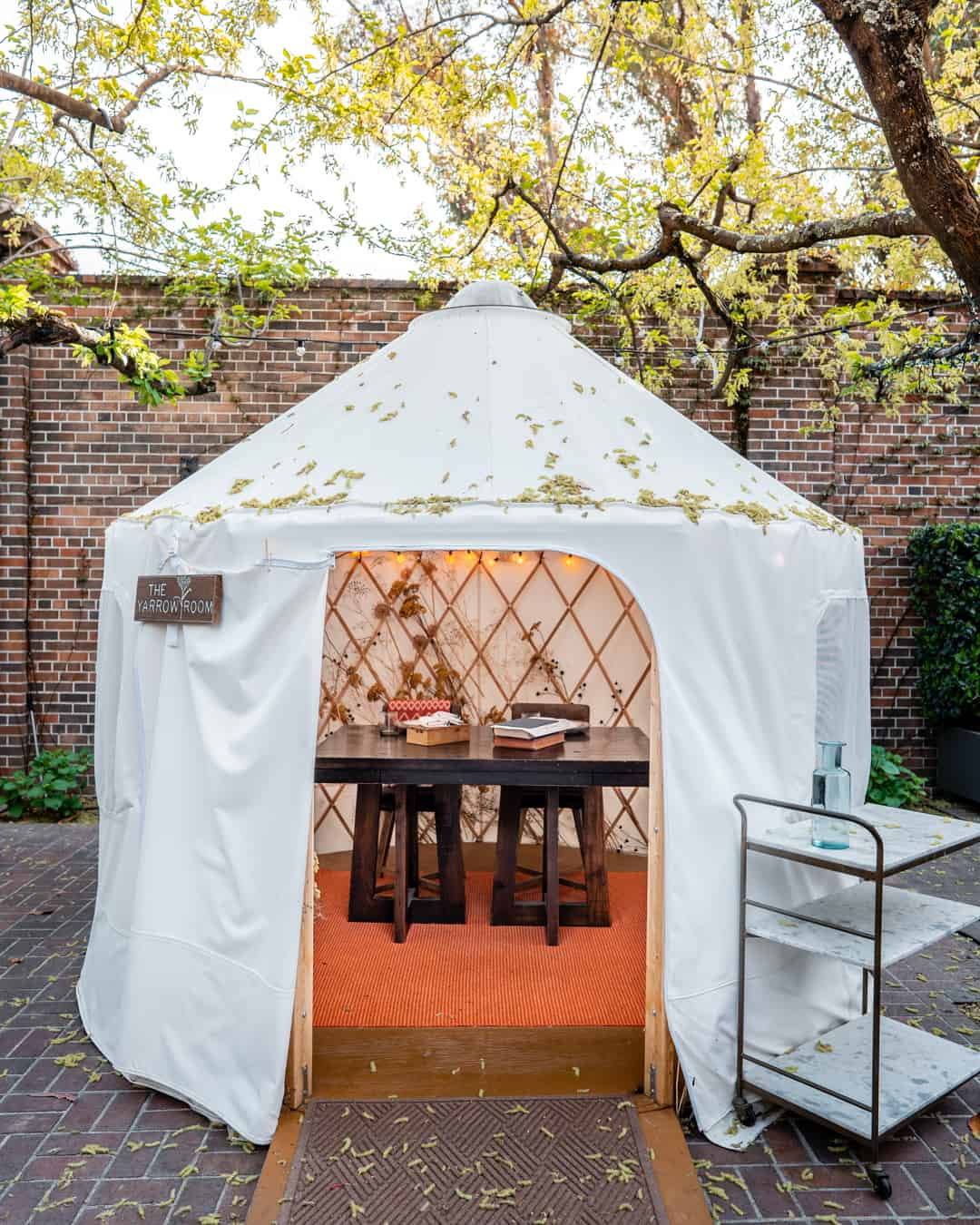 Outdoor yurt dining area with table and chairs.